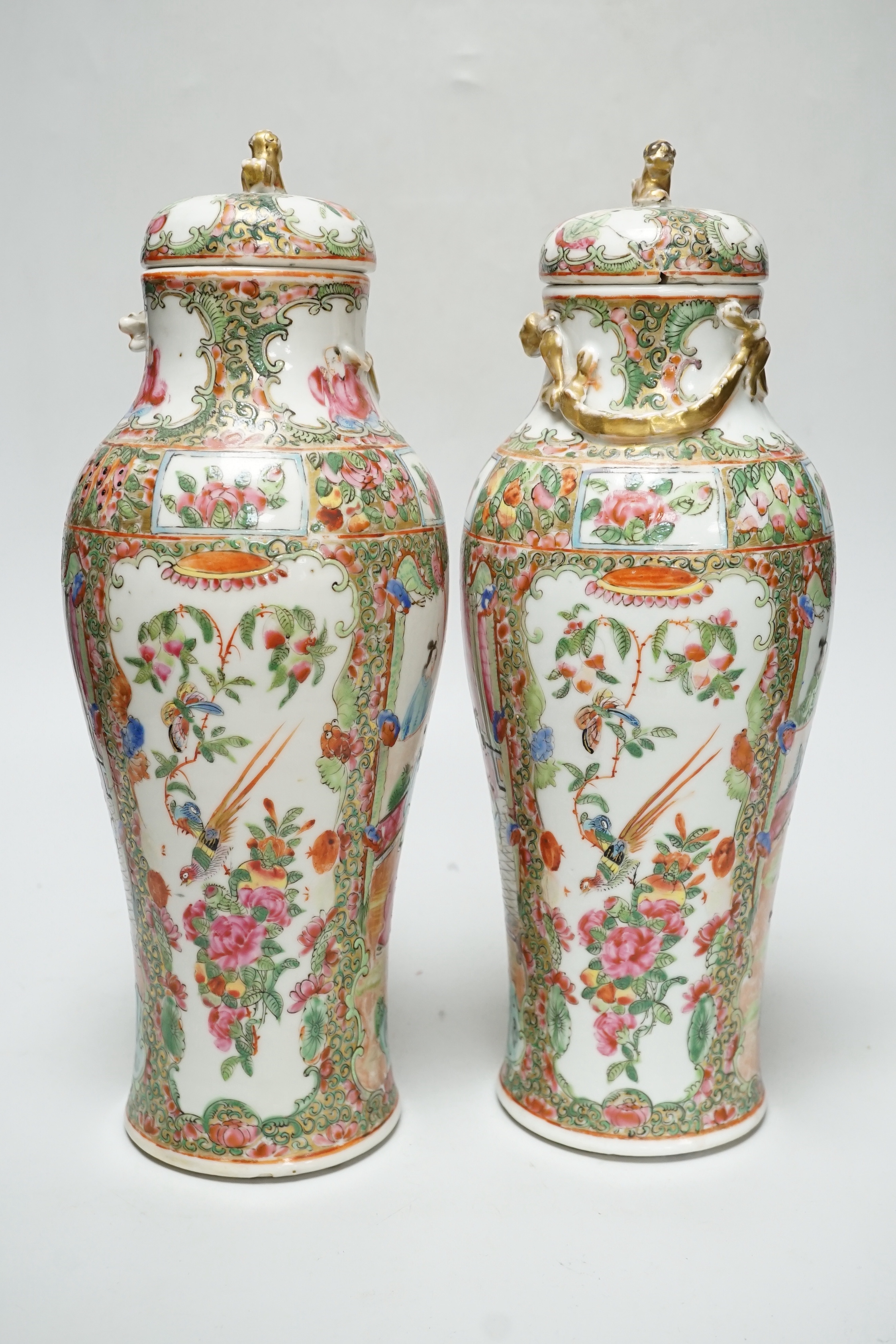 A pair of Chinese famille rose Canton baluster jars and covers with lion dog finials, 32cm high